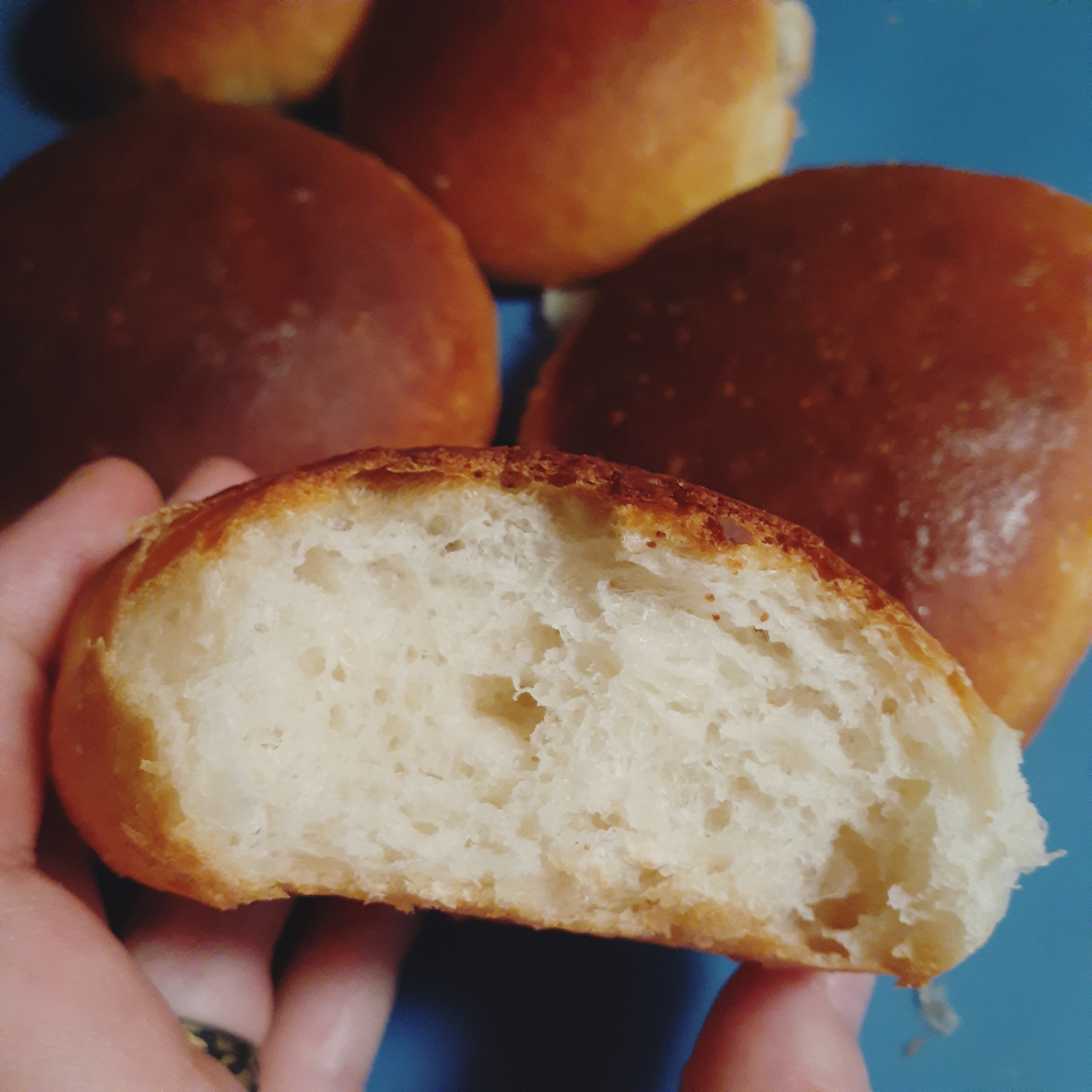 Bread roll with bite taken in front of blue silicone baking mat